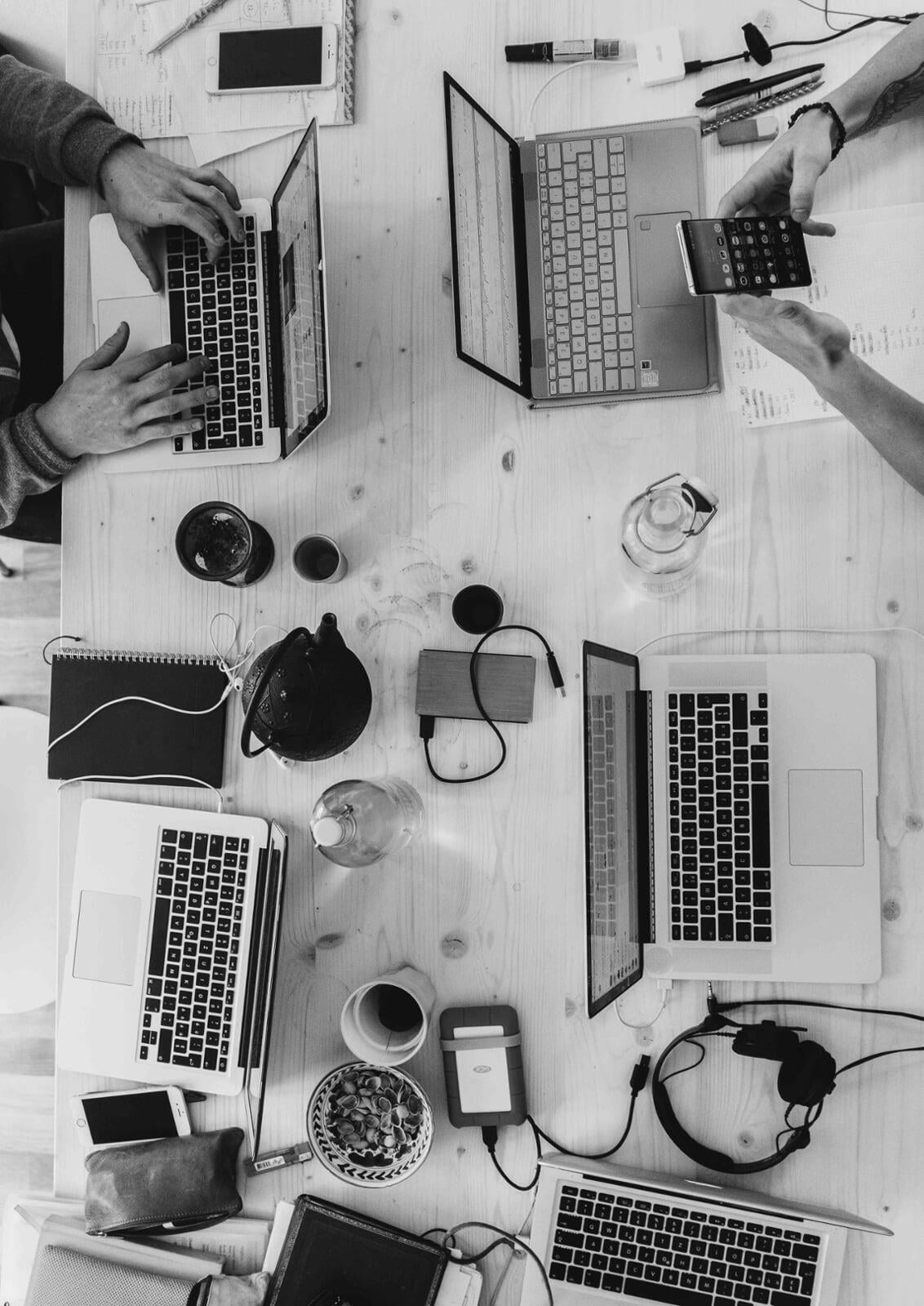 overhead shot of desk with 5 students laptops